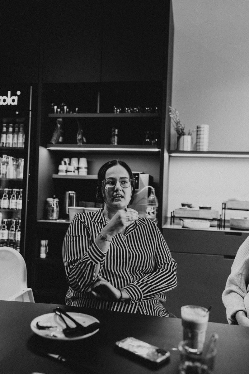 Een vrouw vertelt aan tafel tijdens een brunch (zwart-wit)