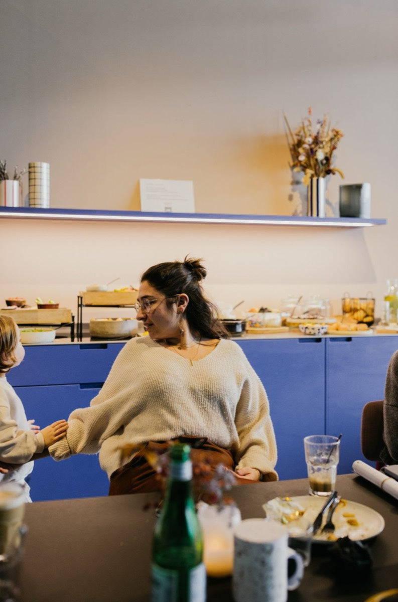 Een mama in gesprek aan tafel, met het buffet op de achtergrond